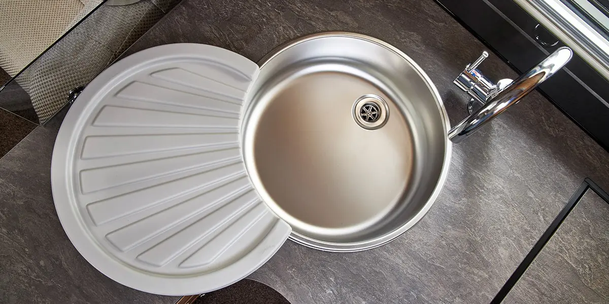 Stainless steel round kitchen sink with concealed fixings, swan-neck mixer tap, washing up bowl and drainer