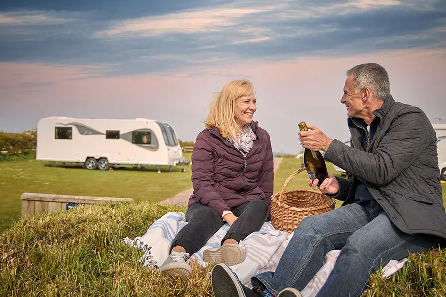 Couple having picnic near their Alicanto Grande caravan