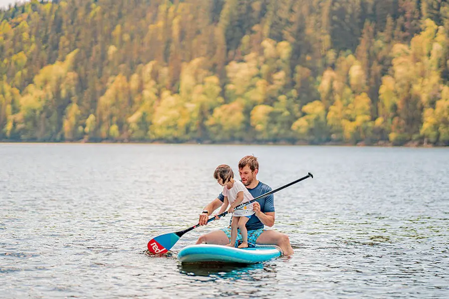 Father and daughter paddleboarding in Cambrian Mountain lake