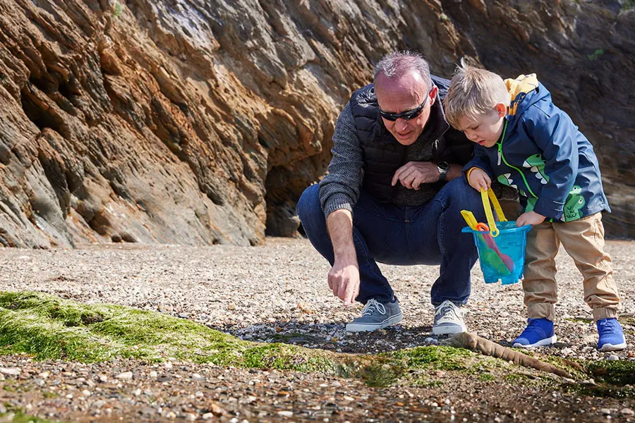 Grandfather and grandson looking in rockpools at Hele Bay