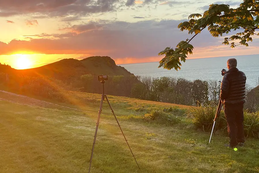 Photographer taking photo of sunset over Little Meadow Campsite in Devon