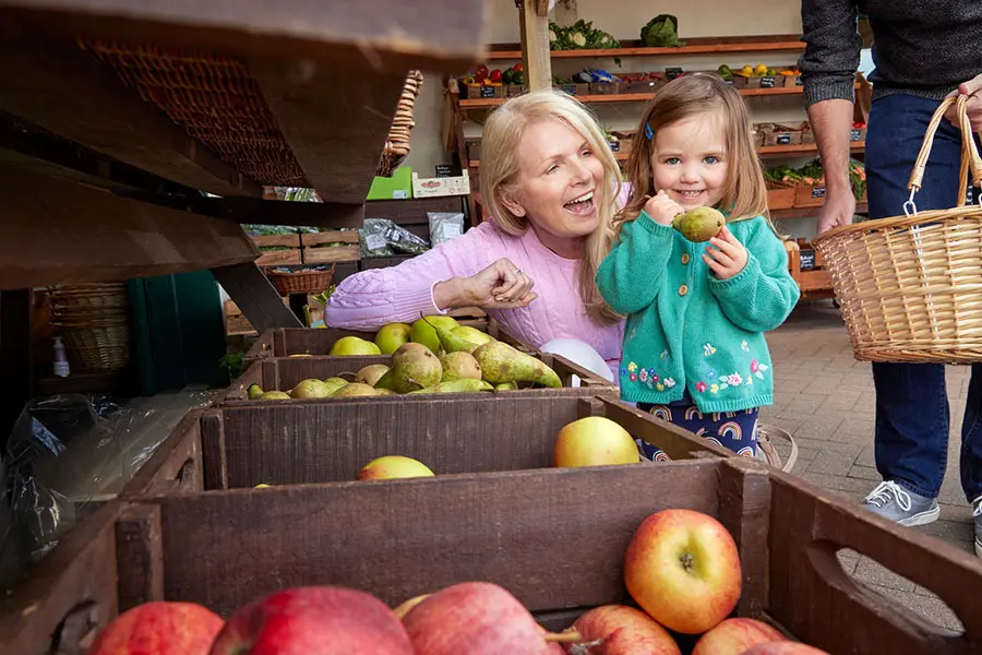 Grandmother and granddaughter buying fruit at local farm shop