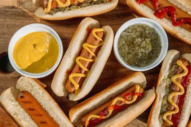 Hot dogs with ketchup and mustard on a wooden chopping board