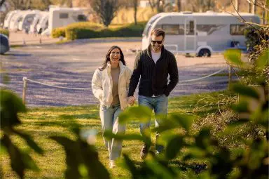 A couple walking through a countryside campsite