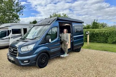 Bailey Endeavour B62 campervan parked at a Brit Stops location in with a traveller standing by the open side door.