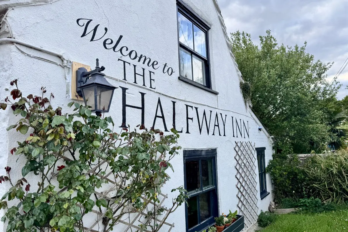 Exterior wall of The Halfway Inn in Wareham, Dorset, with painted pub signage and garden plants and is part of the Brit Stops network of hosts.