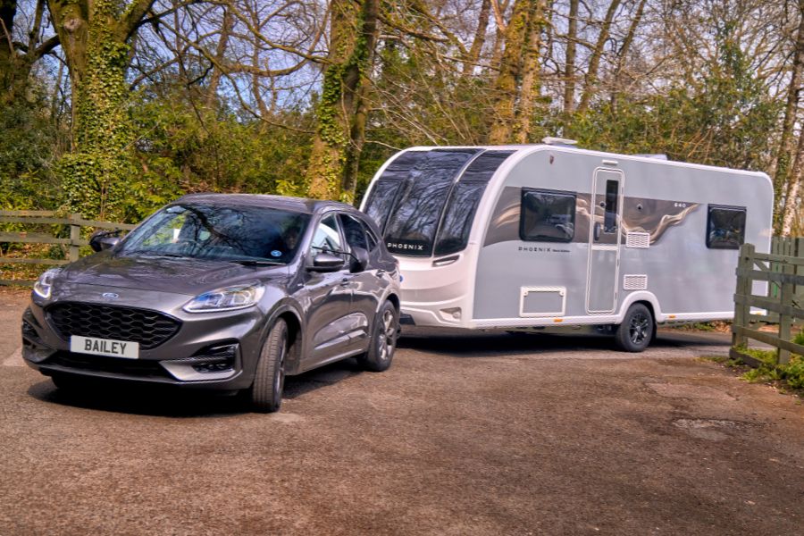Front-side view of the Phoenix Black Edition 640 being towed by a Bailey-branded SUV, showcasing its sleek aerodynamic shape and modern Black Edition graphics.