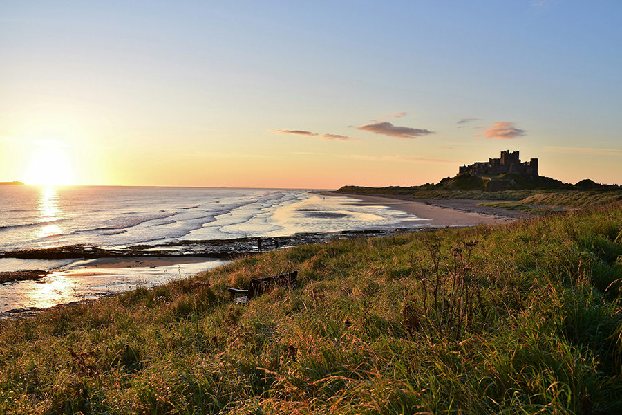 A picture of the Northemberland coast & countryside, looking over to a castle. Photo by Bruce Edwards on Unsplash