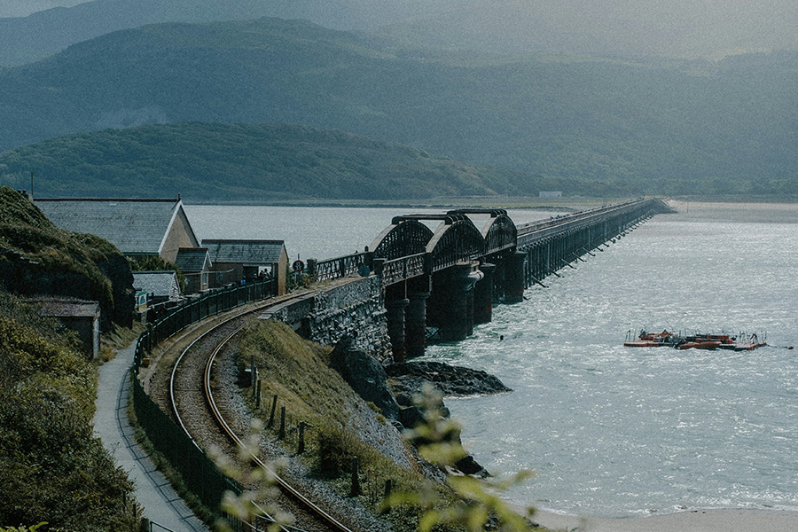 The iconic Barmouth Bridge stretching over a waterway. Photo by Mitchell Orr on Unsplash